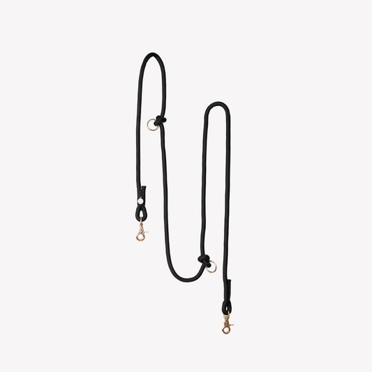 Black hands-free dog leash with gold hooks on a white background