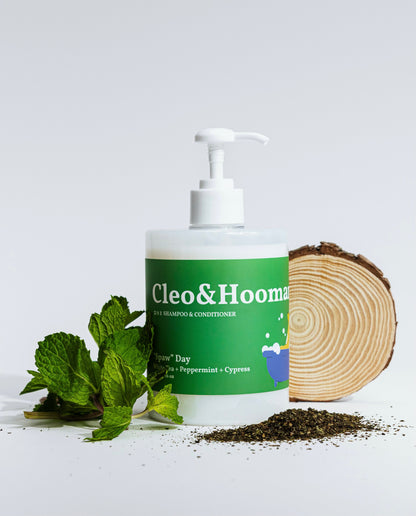 Bottle of Cleo & Hooman shampoo and conditioner with natural elements on a white background