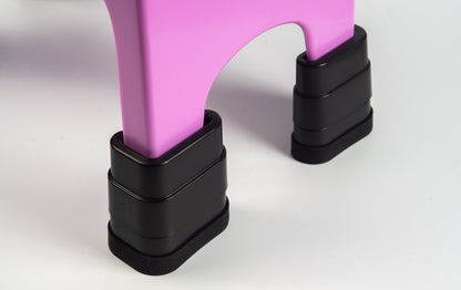 Close-up of two black stackable lifts fitted over the legs of a pink Fluff Trough.