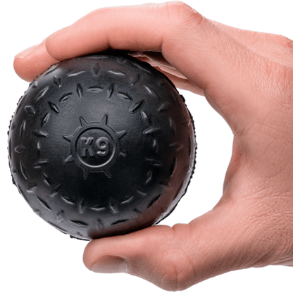 Hand holding a black textured ball with 'K9' branding on a white background